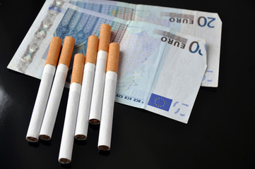 Cigarettes and money on black background