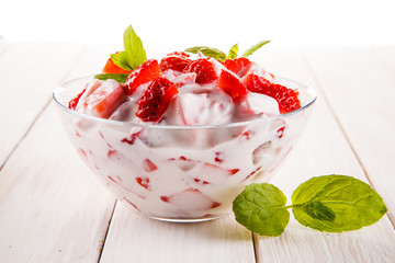 Yogurt with strawberries on wooden background