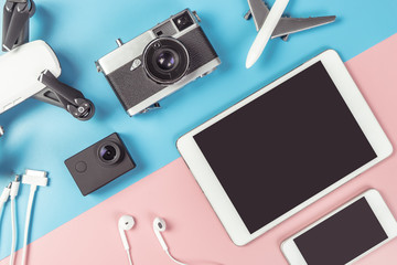 Travel gadgets flatlay on blue and pink background for travel concept