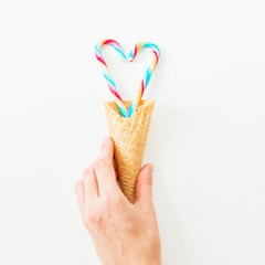 Bright candy cane and waffle cone on white background. Flat lay, top view