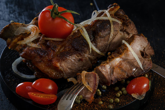 Fried lamb with vegetables. Fried meat on a black background. BBQ. Closeup. Piece of meat on the fork