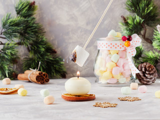 toast a marshmallow over a candle for Christmas and New Year on a wooden white table, selective focus