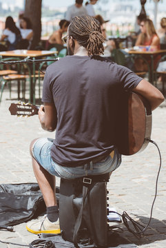 Street Musician Playing And Singing In Outdoor Cafe.