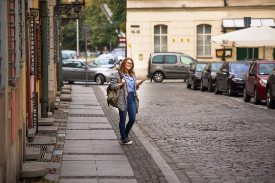Woman traveler with a backpack and phone walks along the street of an ancient European city