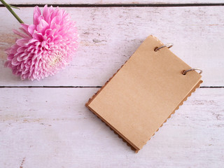 Chrysanthemum flower and blank vintage notepad on wooden background. Top view. Filtered image.