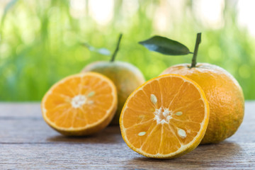 Orange cut half and full ball on wooden floor.