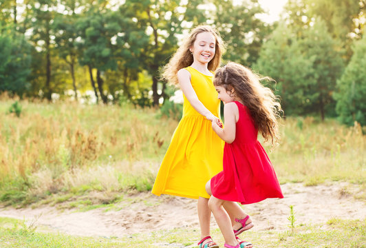 Two Happy little girl embracing and dancing at sunny summer day
