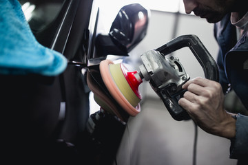 Car detailing - Hands with orbital polisher in auto repair shop. Selective focus.