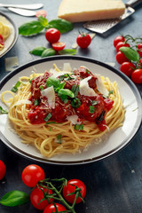 Spaghetti pasta meatballs with tomato sauce, basil, herbs parmesan cheese on dark background