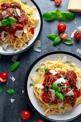 Spaghetti pasta meatballs with tomato sauce, basil, herbs parmesan cheese on dark background