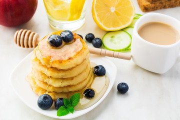 Homemade pancakes with honey, fresh berries and cup of coffee