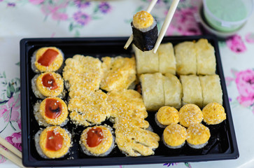 black container with sushi and rolls