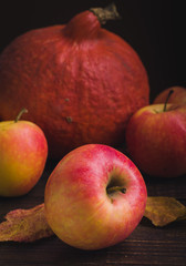 Pumpkins, apples and autumn leaves at wooden background.