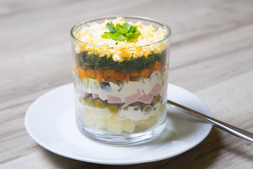 Traditional Russian salad Olivier with sausage in a glass. Selective focus, close - up.