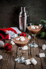 Ideas for Christmas party drinks, homemade Hot Chocolate Martini cocktails with marshmallow, on old rustic wooden table with christmas decorations, copy space