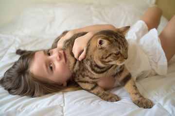 Caucasian girl hugging cat on bed