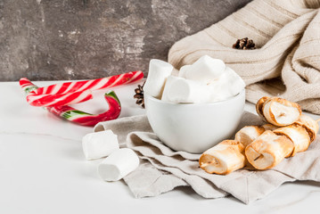 Traditional christmas sweets - candy cane, marshmallow and baked on fire marshmallow skewers on white background, copy space