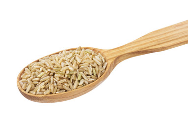 Brown rice groats in wooden spoon isolated on white background