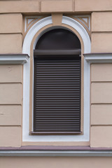 Arched window in classical style with jalousie. Architecture