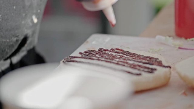 Closeup slow motion shot of chef preparing tasty burgers at outdoor stand. Sauce barbecue, fast food industry and unhealthy lifestyle concept.
