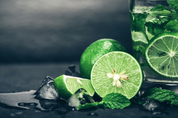 Close up the fresh mojito cocktail with fresh lime and mint leaf on black stone background
