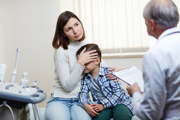 Fototapeta premium Young mother talking to doctor about health of her little son