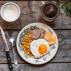 fried egg, cheese, sausage, corn and other products on a wooden surface