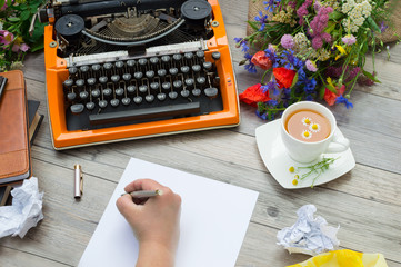 Orange vintage typewriter with a hand of writer.
