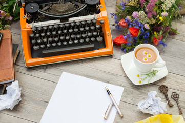 Orange vintage typewriter with a cup of herbal tea and old keys.