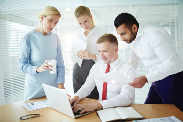 Fototapeta premium Group of business people watching teleconference in front of laptop in office