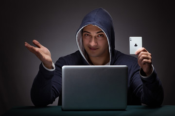 Young man wearing a hoodie sitting in front of a laptop computer