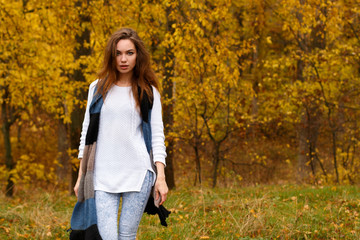 Young girl with long brow hair in autumn park
