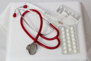 Czerwony stetoskop na białym tle pośród leków i strzykawek zdjęcie od góry 