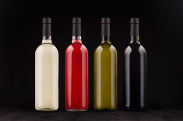 Fototapeta na wymiar Wine bottles collection different colors, mock up on elegant dark black wooden background. Template for portfolio, advertising, design.