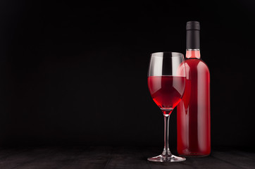 Bottle of rose wine and wine glass mock up on elegant dark black wooden background, copy space.