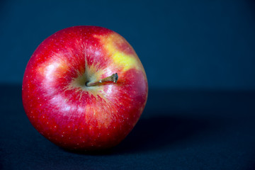 Whole, red, ripe, tasty apple with its stem pointing right on black background