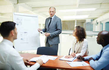 Confident trader by whiteboard making reprt for his employees at seminar