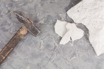 One broken white stone and him fragments and old dirty hammer with wooden handle on background of...