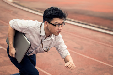 businessman is holding computer laptop while he is running on run lane. business man in action of beginning startup to run. start up business run to goal setting concept.