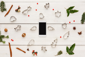 Smartphone and cookie cutters on white wooden table, top view