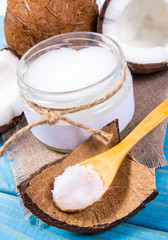 Coconut oil and fresh coconuts on a wooden table.