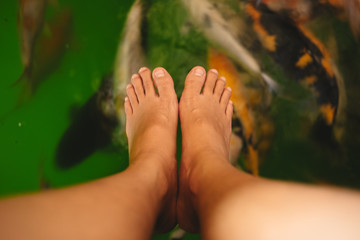 top view. bare foot of young women has carp fishes in water are background . this image for life, pet, animal, body, nature, abstract concept