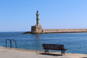 Lighthouse view with an empty bench in the old Venetian Harbor of Chania, in Crete Island, Greece.