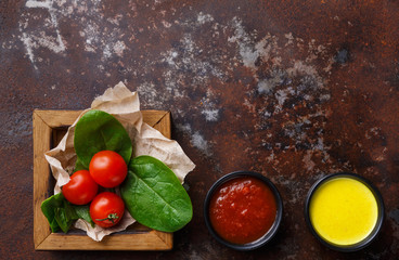 Tomatoes and basil leaves with sauces top view