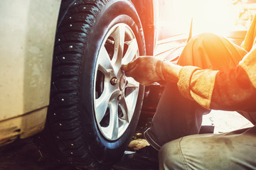 Car mechanic worker doing tire or wheel replacement in garage of repair service station © DedMityay