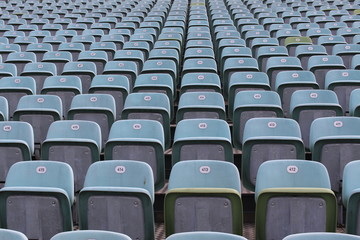 Fototapeta premium Rows of numbered empty plastic seats at an open-air amphitheater.