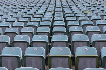 Rows of numbered empty plastic seats at an open-air amphitheater.