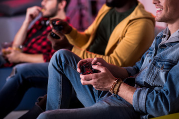 Adult entertainment. Close-up of hands with joystick of young man who is playing home video game...
