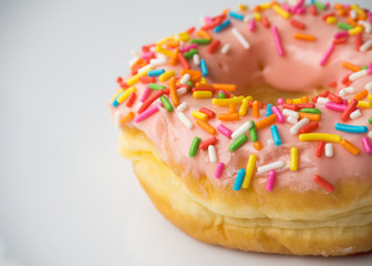 Donut with strawberry chocolate topping and colorful sugar breads on white background.