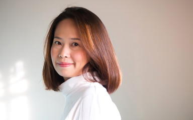 Chubby asian woman in white Turtle Neck T-shirt smiling. Portrait on white background with nature light. Copy space.